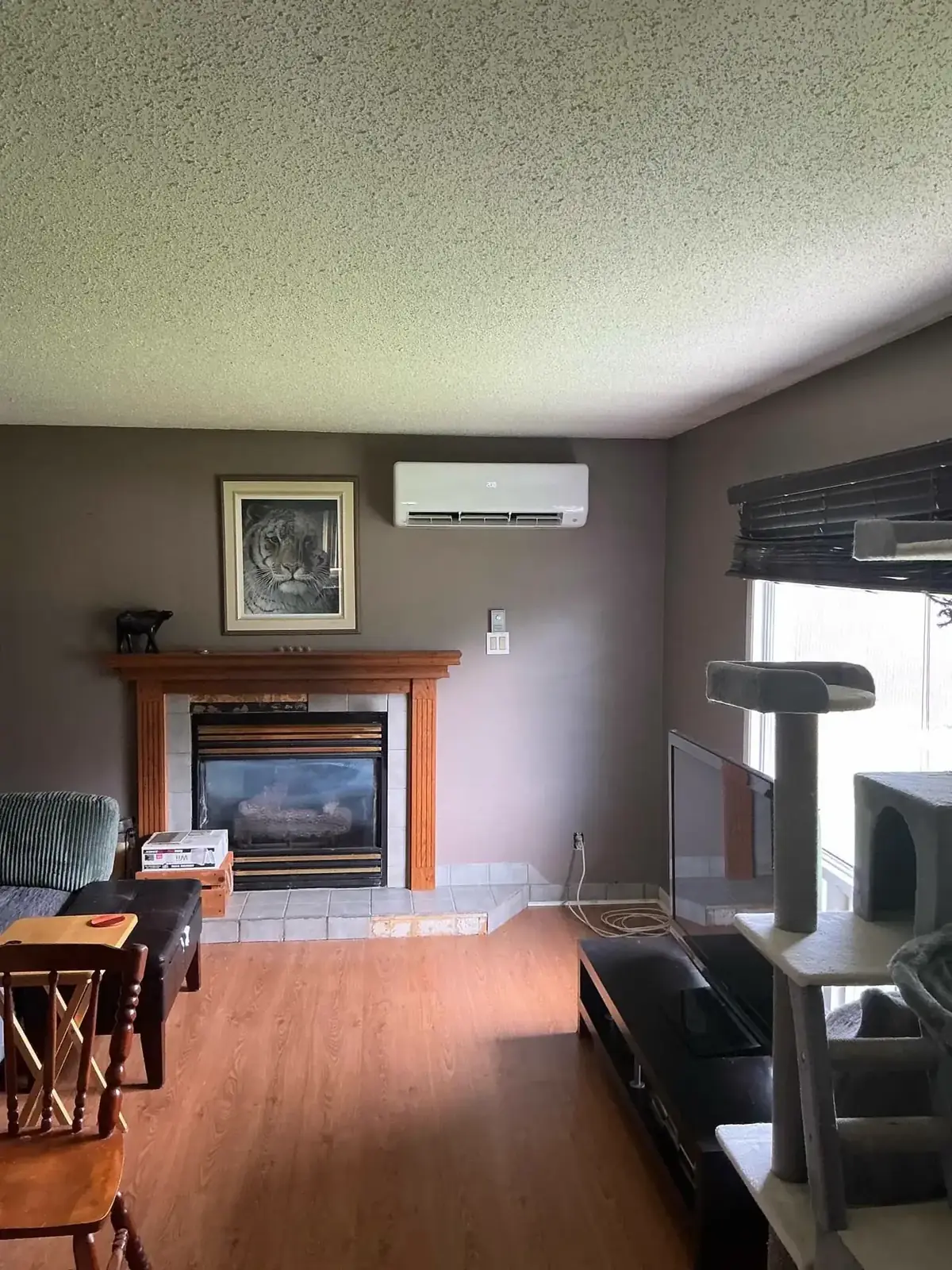 Wall-mounted heat pump head installed above a fireplace